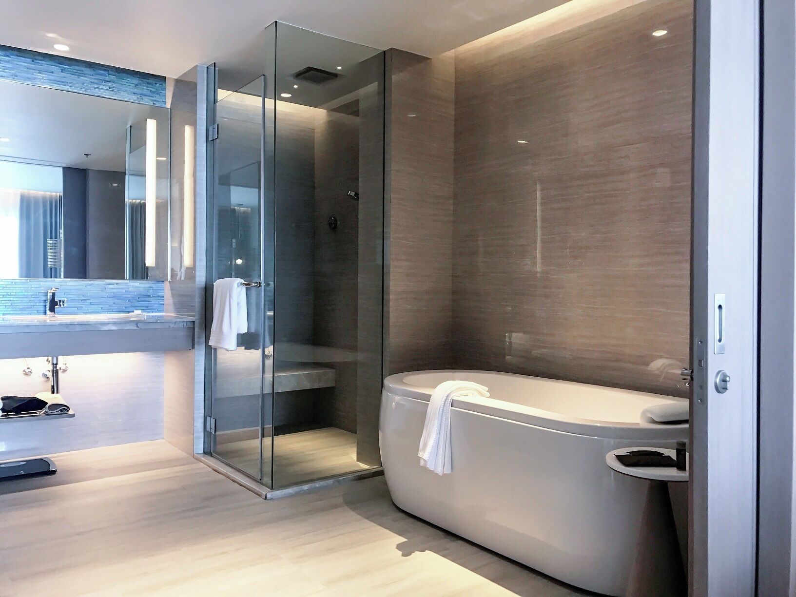 Un baño moderno con ducha envuelta en vidrio, bañera independiente y tocador con espejo.