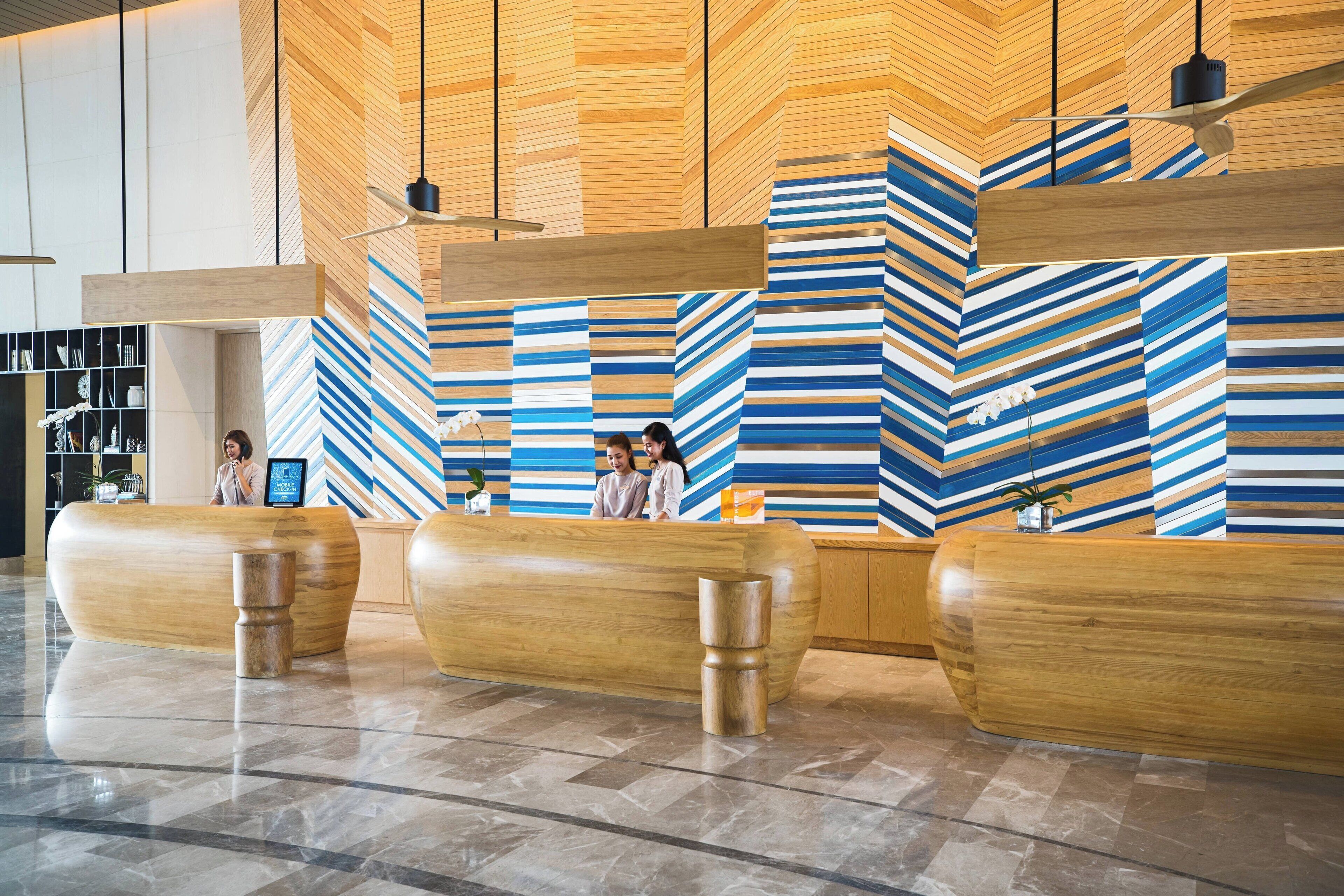 A reception area with a modern design, featuring a wooden reception desk and a chevron-patterned wall.