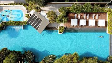 A rooftop swimming pool with a sun terrace, surrounded by lush greenery.