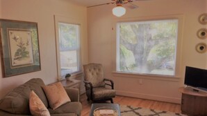Una sala de estar con sofá, sillón, mesa de centro y televisor.