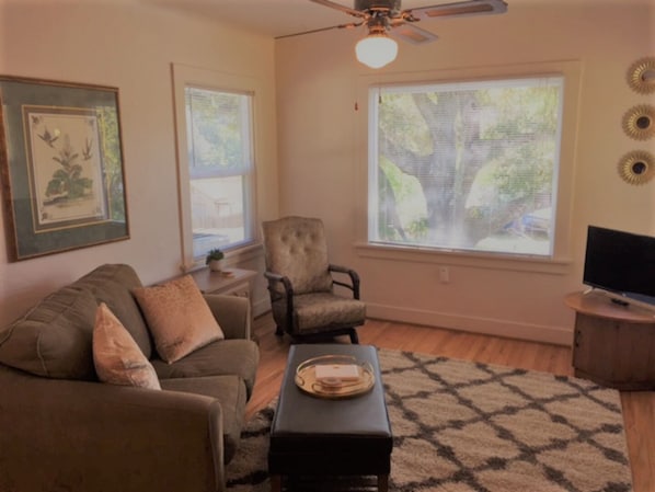 A living room with a sofa, armchair, coffee table, and a television.