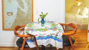 Un'area pranzo con un tavolo apparecchiato per due, una sedia di legno, un vaso con fiori e una grande mappa appesa al muro.