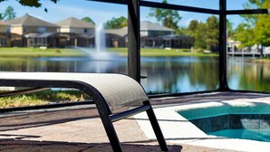 A poolside area with a chair, a view of a fountain, and a body of water. - Comfortable 4bdr w/private pool - No resort fees (Kissimmee)