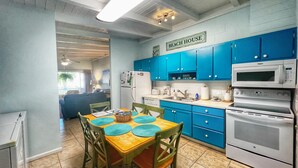 A kitchen with blue cabinets, a wooden dining table with chairs, a refrigerator, a microwave, and an oven. - A Beach, Golf, Tennis and Fun for the whole family Sandy Toes & Salty Kisses A (Jekyll Island)