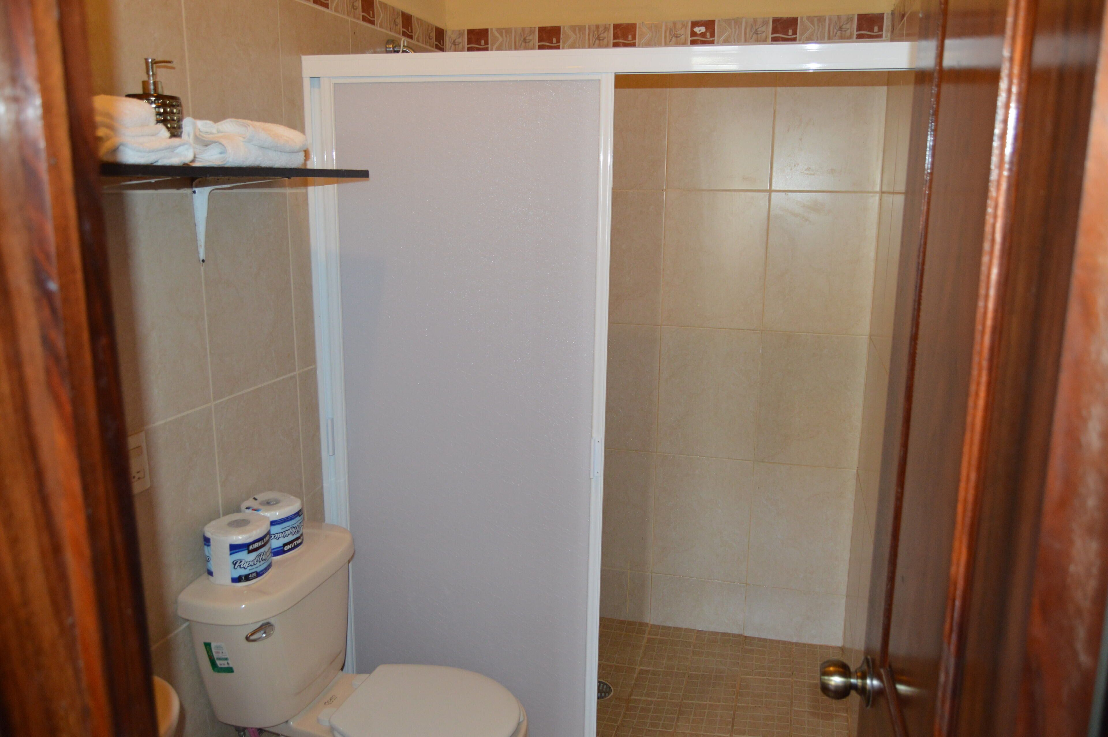 Une salle de bain comprenant des toilettes, un espace douche et un porte-serviettes avec des serviettes.
