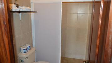 Une salle de bain comprenant des toilettes, un espace douche et un porte-serviettes avec des serviettes.
