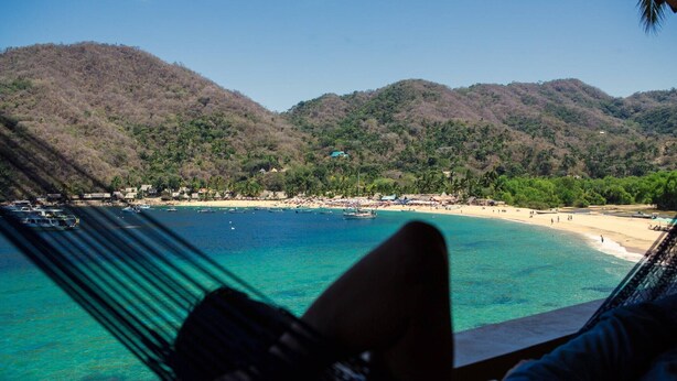A beach view with clear turquoise water, a hammock, and a mountainous backdrop. - Oceanfront Yelapa (yelapa)