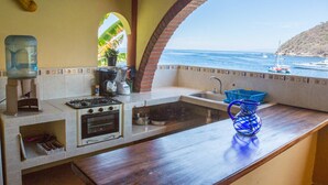 A kitchen with a view of the ocean, a water dispenser, a coffee maker, and a sink. - Oceanfront Yelapa (yelapa)