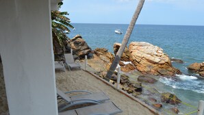 A beach with lounge chairs, a palm tree, and a rocky shoreline. - Oceanfront Yelapa (yelapa)