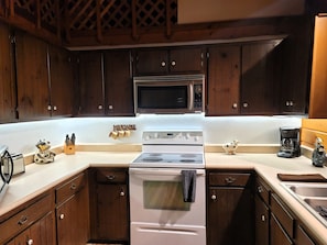 A kitchen with wooden cabinets, a microwave, a stove, and a coffee maker.