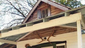 Un chalet rustique doté d’une véranda, d’une porte en bois et d’une pancarte accueillante.