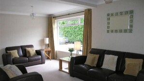 A living room with two black leather sofas, a small wooden coffee table, and a lamp.