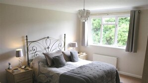 A bedroom with a bed, bedside tables, lamps, a radiator, and a window with curtains.