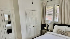 A bedroom with a bed, a nightstand, a lamp, a window with curtains, and a door. - Beautiful Updated Historic 3BD/2BTH Home (Birmingham)