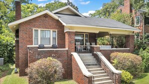 A two-story brick house with a covered porch, a front yard, and a staircase leading to the entrance. - Beautiful Updated Historic 3BD/2BTH Home (Birmingham)