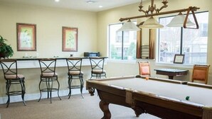 A pool table in a room with a bar area, chairs, and large windows. - Baton Rouge Condo With Resort Atmosphere With Custom Decor, Sleeps 2 (Baton Rouge)