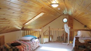 A cozy attic bedroom with two beds, a wooden ceiling, and a fan. - The Cedar House Is Uniquely Set In The Forest Surrounded By Decks And Porches. (McGrath)