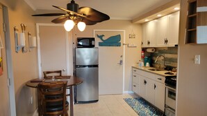 A compact kitchen with a refrigerator, microwave, and stove. There is a dining table with chairs and a ceiling fan. - Romantic Beach Getaway For 2 In Ocean City MD (Ocean City)
