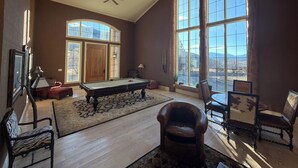 A spacious room with a pool table, leather chairs, and large windows offering a mountain view. - Expansive 6-Bedroom Lodge with gorgeous mountain views. Perfect for large groups (Livingston)