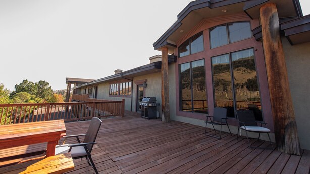 A deck with a grill, chairs, and a table. - Expansive 6-Bedroom Lodge with gorgeous mountain views. Perfect for large groups (Livingston)