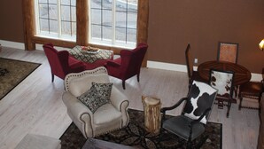 A living room with a large window, a fireplace, and a coffee table with books. - Expansive 6-Bedroom Lodge with gorgeous mountain views. Perfect for large groups (Livingston)