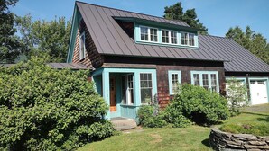 Une maison à deux étages avec un toit en pente, un porche doté d’une porte et un garage.