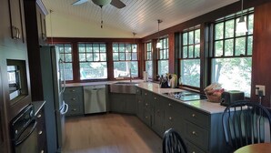 Une cuisine avec des meubles de rangement en bois, un four encastré, un évier et un ventilateur de plafond.