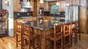 A kitchen with wooden cabinets, a central island with bar stools, stainless steel appliances, and a window providing natural light. - Bend Country 4 BR/3 Bth, Amazing 9 Mt View, 9 acre, Peaceful Getaway (Terrebonne)