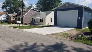 A residential house with a garage, a front porch, and a driveway. - Wampler's Lake in Brooklyn, MI close to MIS with access to dock (Brooklyn)