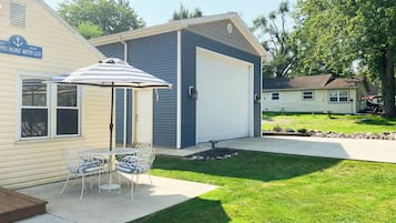 Enjoy the serene atmosphere of this residential property, featuring a beautifully maintained lawn and patio area with outdoor furniture.