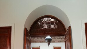An arched doorway leading to a dining area with a red carpet and a hanging lantern.