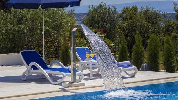 A pool with a water feature, lounge chairs, and an umbrella. - Villa Tramonto (Seget)