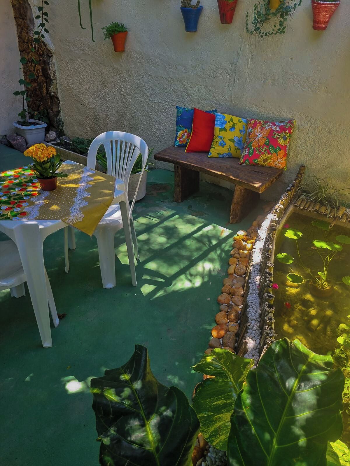 Un patio con mesa, sillas, banco y una pequeña fuente.