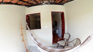 A room with a hammock, a wooden coat rack, and two open doors leading to other rooms. - Residencial Porto de Galinhas (Ipojuca)