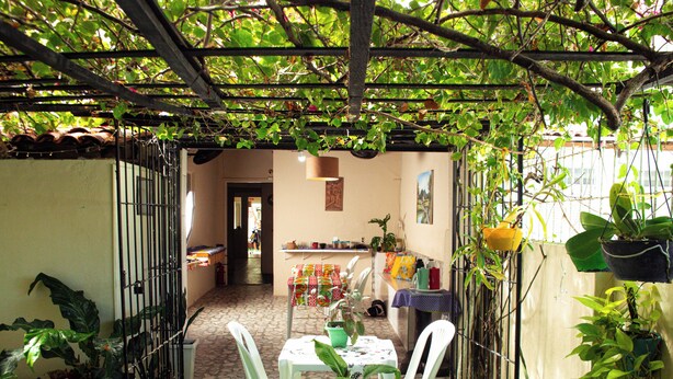 A covered patio area with tables and chairs, surrounded by potted plants and a garden. - Residencial Porto de Galinhas (Ipojuca)