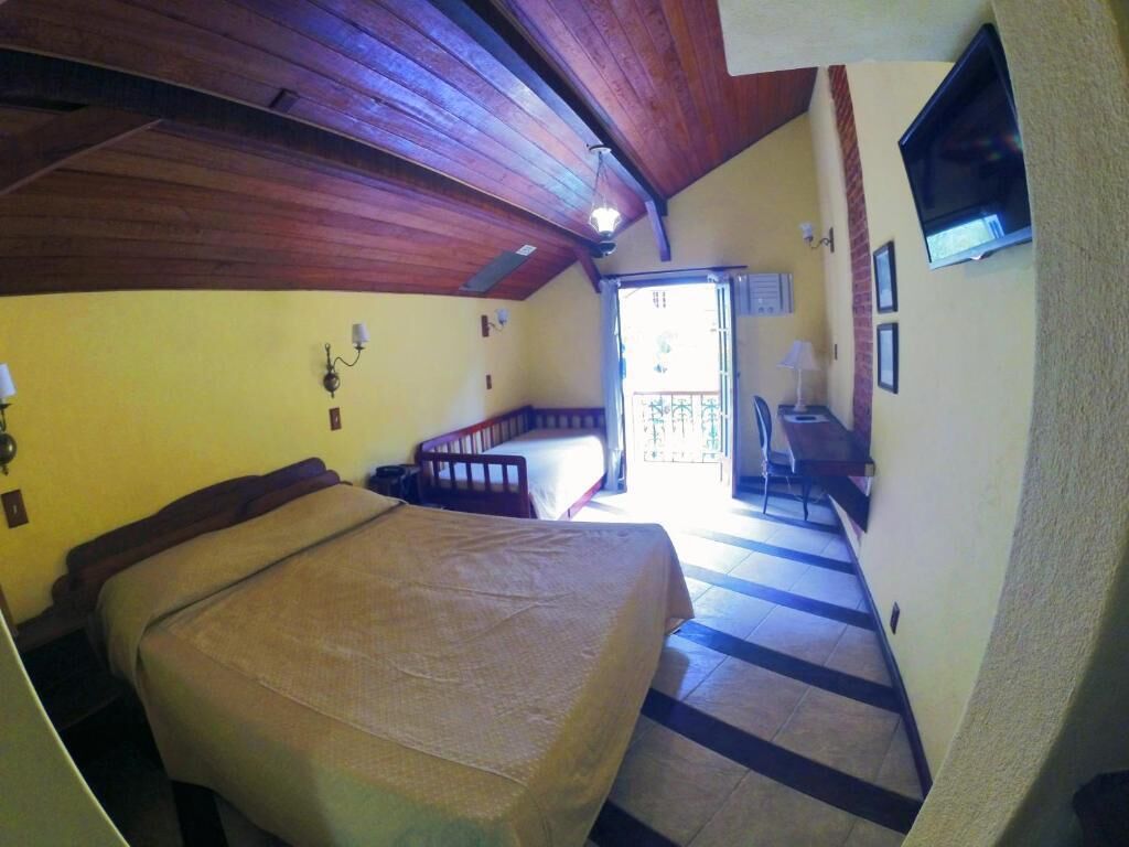 A bedroom with a bed, a desk, and a television.