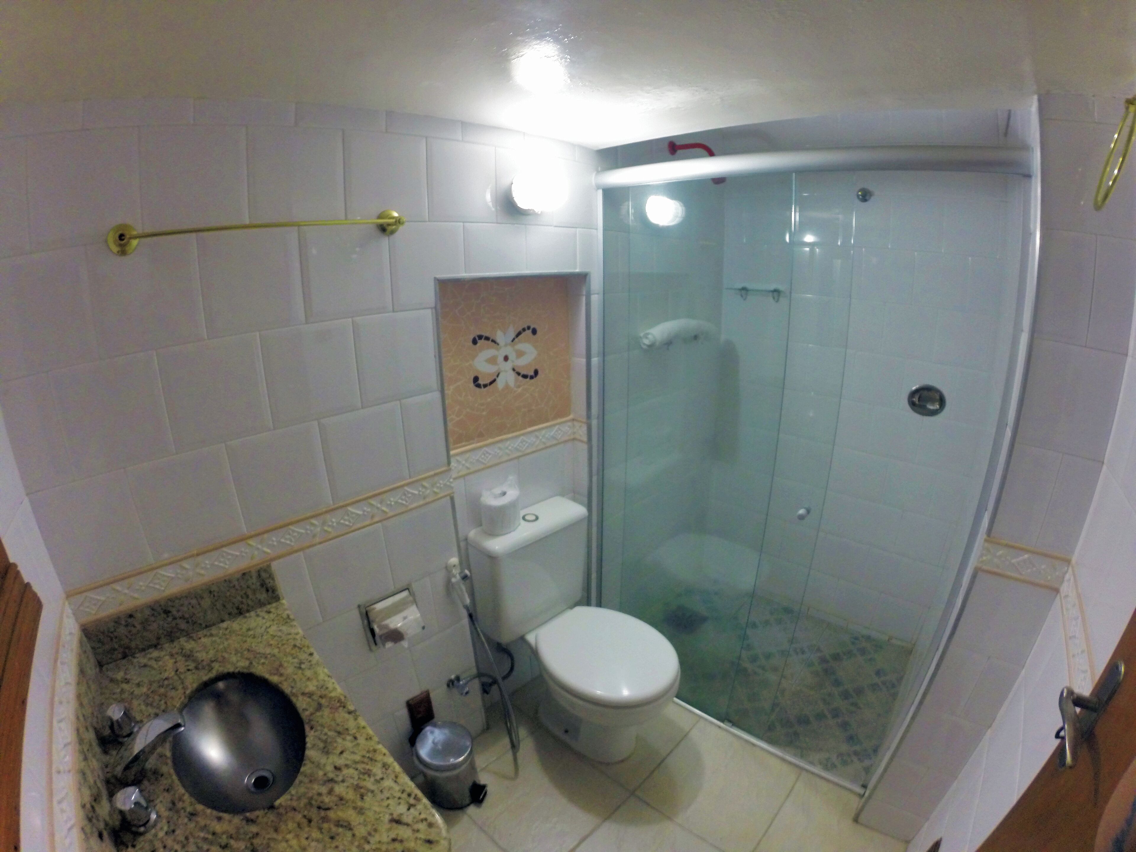 Un baño con ducha de vidrio, inodoro, lavabo y toallero.