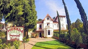 A large, white building with a red roof, surrounded by greenery and a sign reading "Pousada Imperial Koeller". - Pousada Imperial Koeler (Petrópolis)