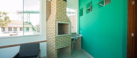 A room with a brick fireplace, a window, a bench, and a green wall.