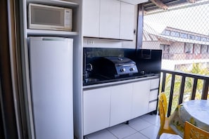 Una cocina funcional con refrigerador, microondas y estufa a gas.