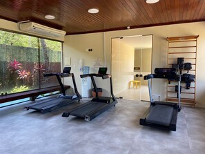 A fitness room with three treadmills, a water dispenser, and a shoe rack.