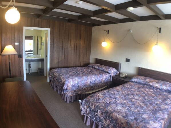 A room with two beds, a wooden table, and a bathroom visible through an open door. - Fountain Inn (Bucksport)