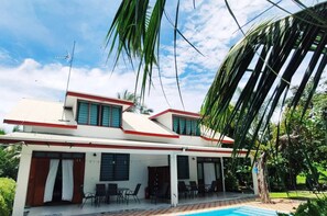 Una casa moderna de dos pisos con un porche cubierto y una piscina.