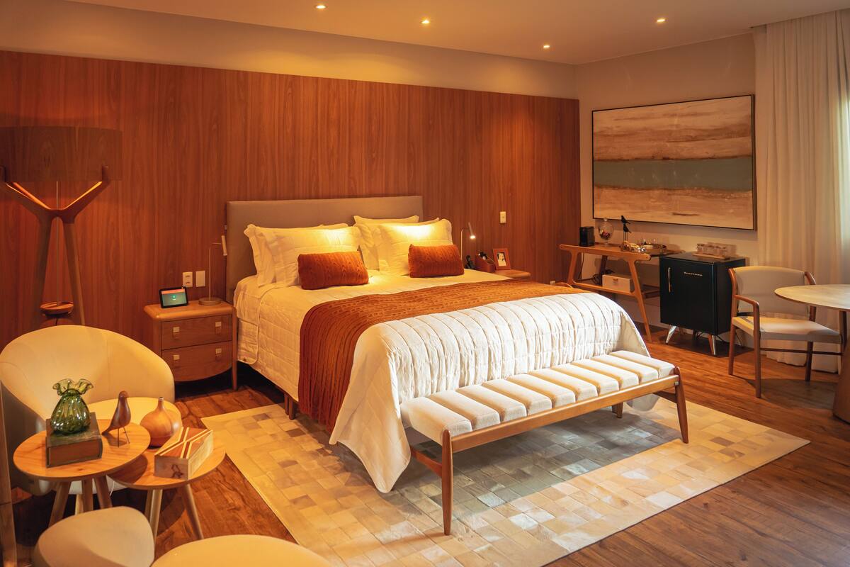 A modern hotel room with a large bed, bedside tables, a desk, and a chair.