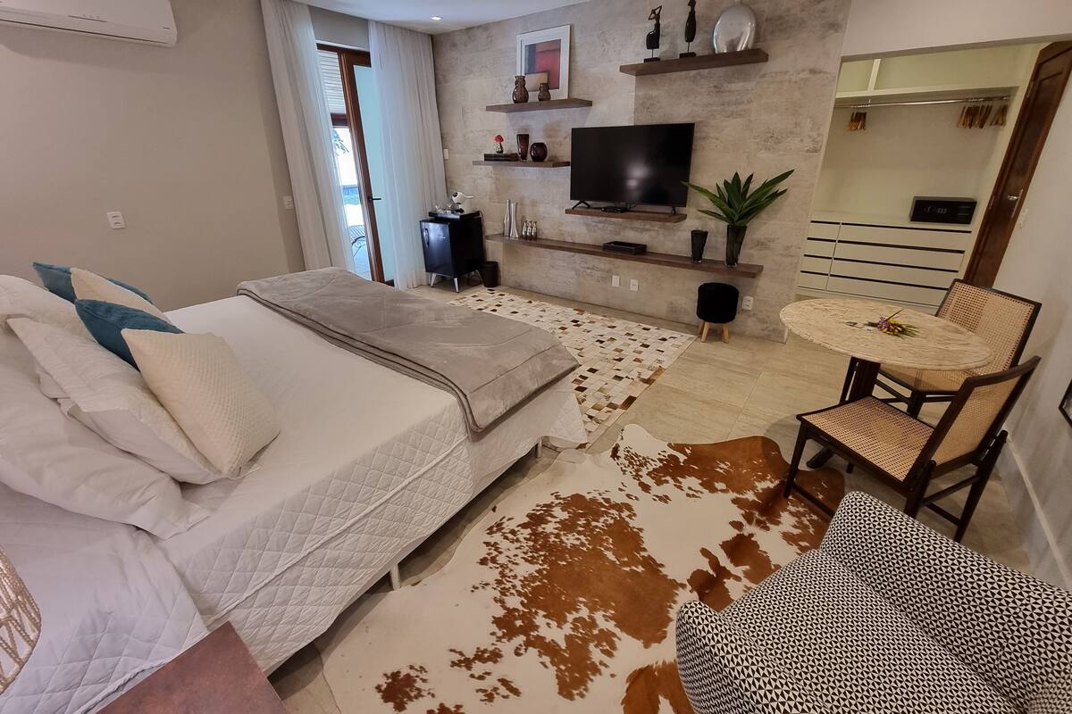 A modern bedroom with a bed, a TV, a small table, and a chair.