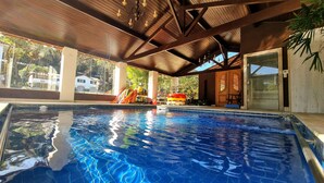 Una piscina interior con techo de madera y vistas al exterior.