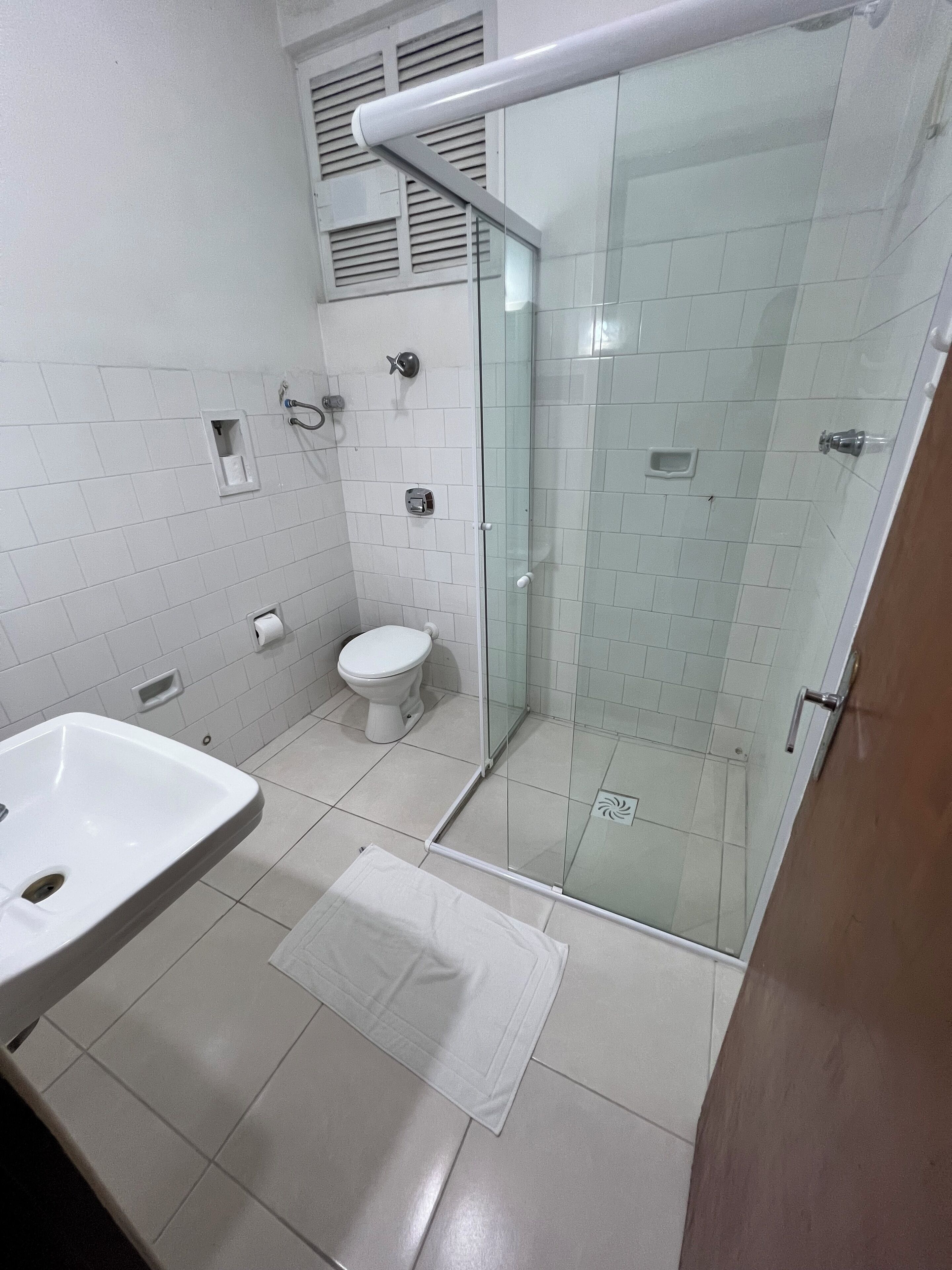 Un bany modern amb dutxa d'ampul·lòpia de vidre, un lavabo blanc i un vàter.