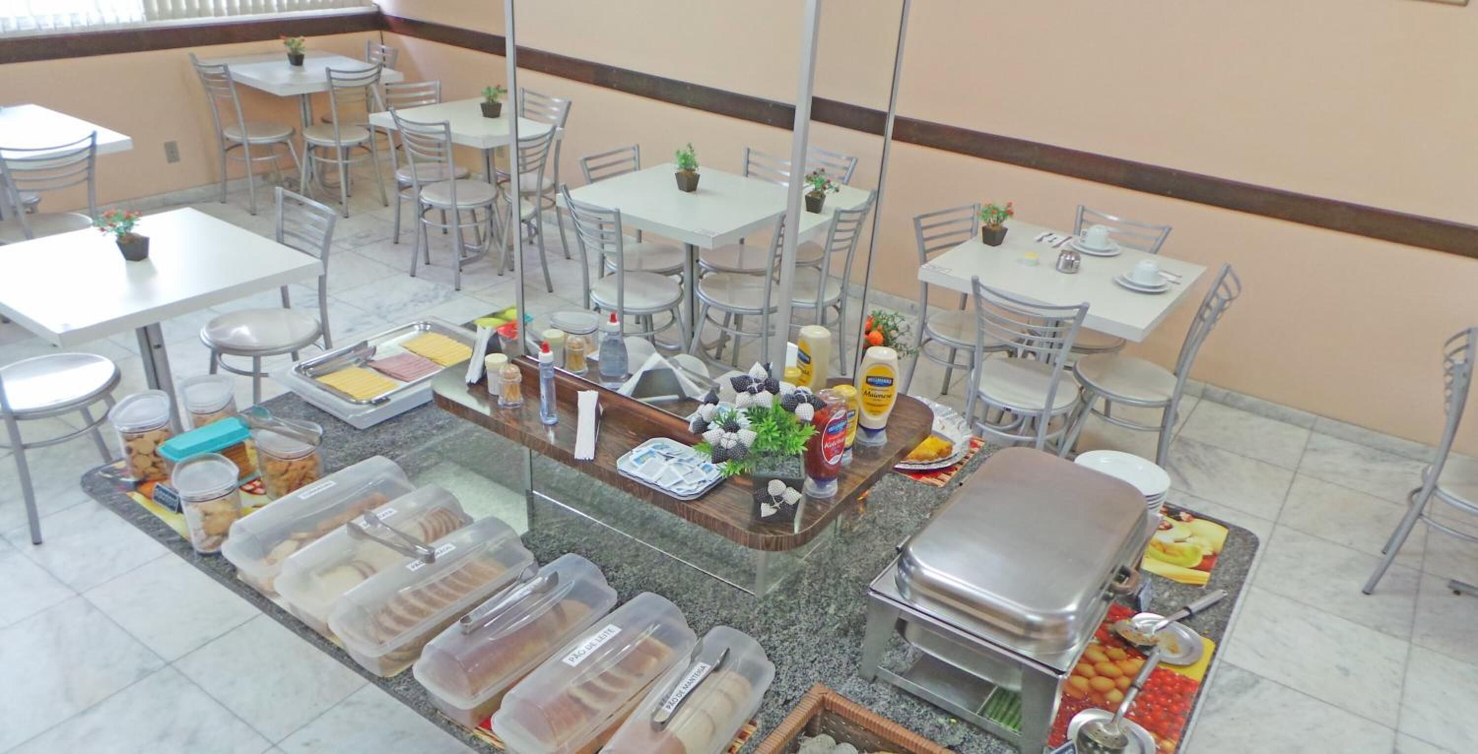 A cafeteria with multiple tables and chairs, food dispensers, and a buffet area.