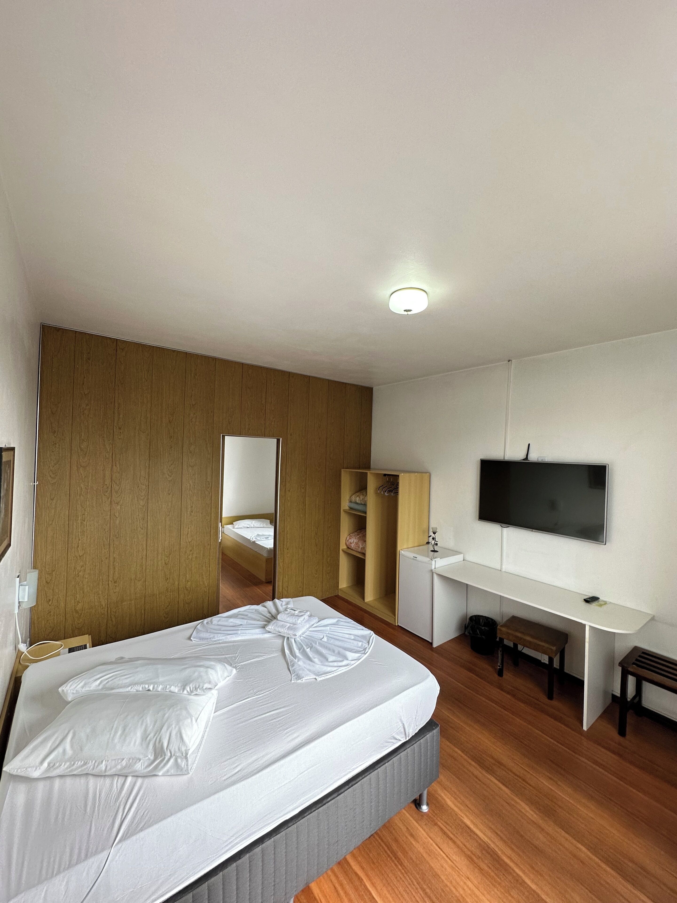Une chambre d’hôtel moderne équipée d’un lit, d’un bureau, d’une télévision et d’une armoire.
