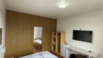 Une chambre d’hôtel moderne équipée d’un lit, d’un bureau, d’une télévision et d’une armoire.